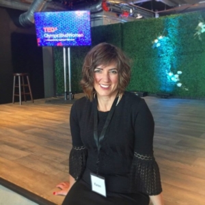 Karen Pery smiling at the camera on stage during her TED talk