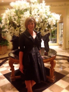 Karen Pery dressed up in a black dress posing near a huge bouquet of lilies