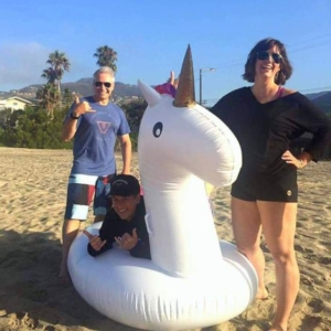 Karen Perry and friends smiling on a beach with a big unicorn blow up floatie
