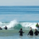 People in wetsuits wading into the ocean